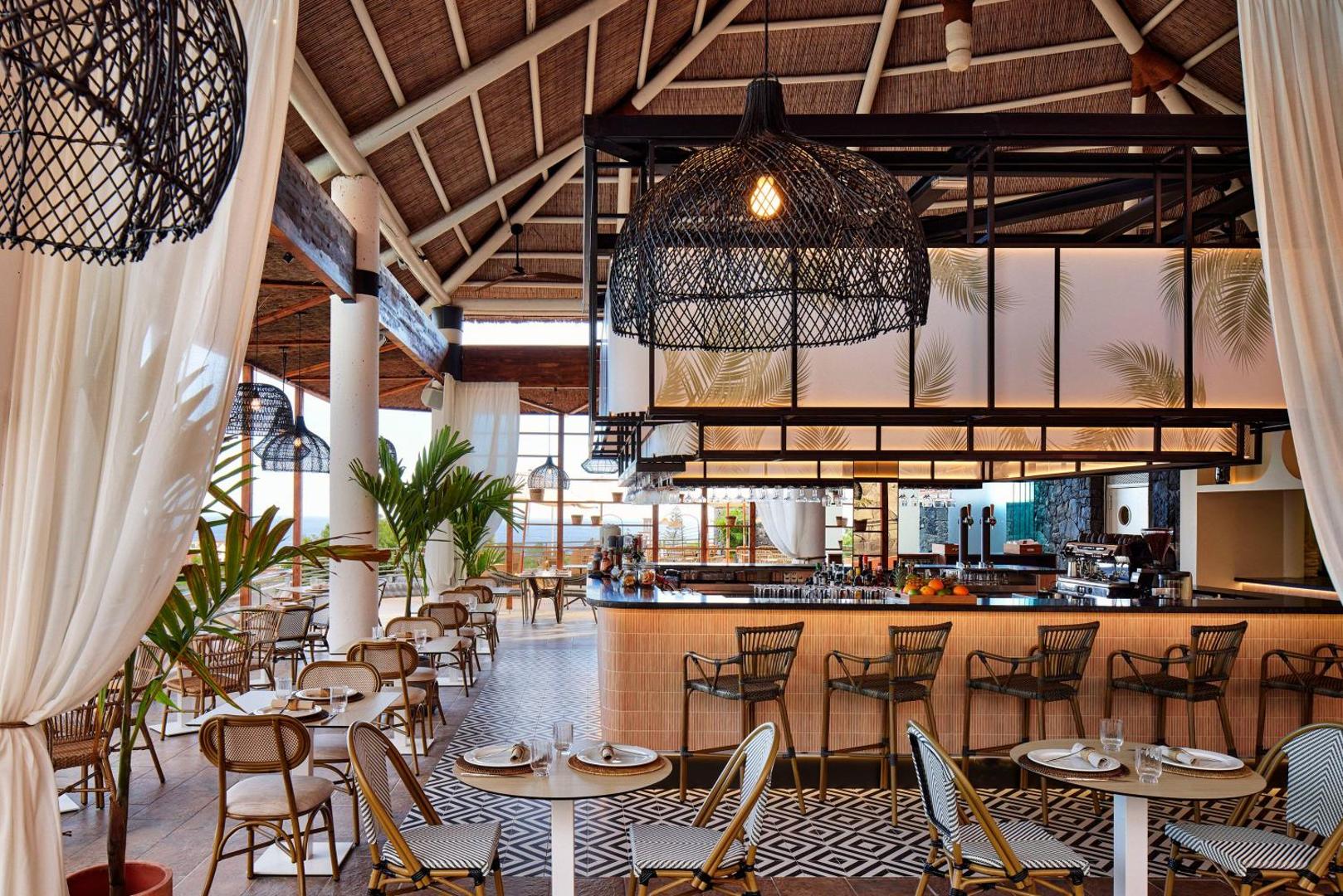 Melia Jardines del Teide viesnīcas bārs un restorāns ar modernu dizainu, pītiem gaismekļiem un gaišām mēbelēm Tenerifē