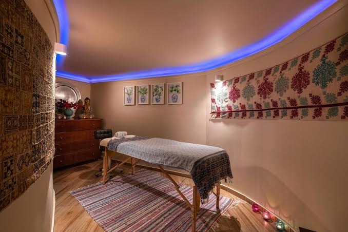Dionysos viesnīcas spa procedūru telpa ar masāžas galdu, austrumnieciskiem dekoriem un zilu griestu apgaismojumu Rodā