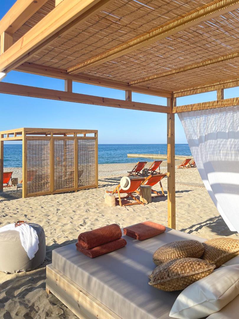 Aquila Rithymna Beach viesnīcas pludmales bungalo stila nojume ar mīkstiem matračiem un skatu uz zilo Vidusjūru Krētas salā.