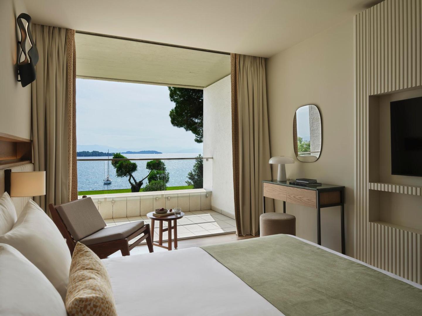 Kontokali Bay Resort & Spa numurs ar skatu uz Jonijas jūru Korfu salā — gaišs interjers, balkons un atpūtas zona