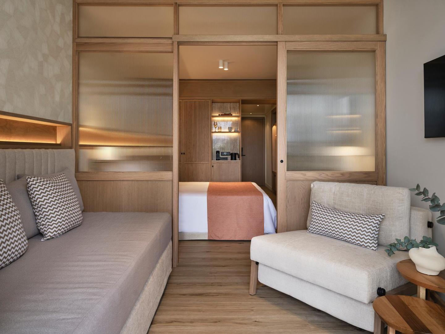 Kontokali Bay Resort & Spa ģimenes numurs ar bīdāmām stikla durvīm un atsevišķu atpūtas zonu — koka apdare un gaiši toņi