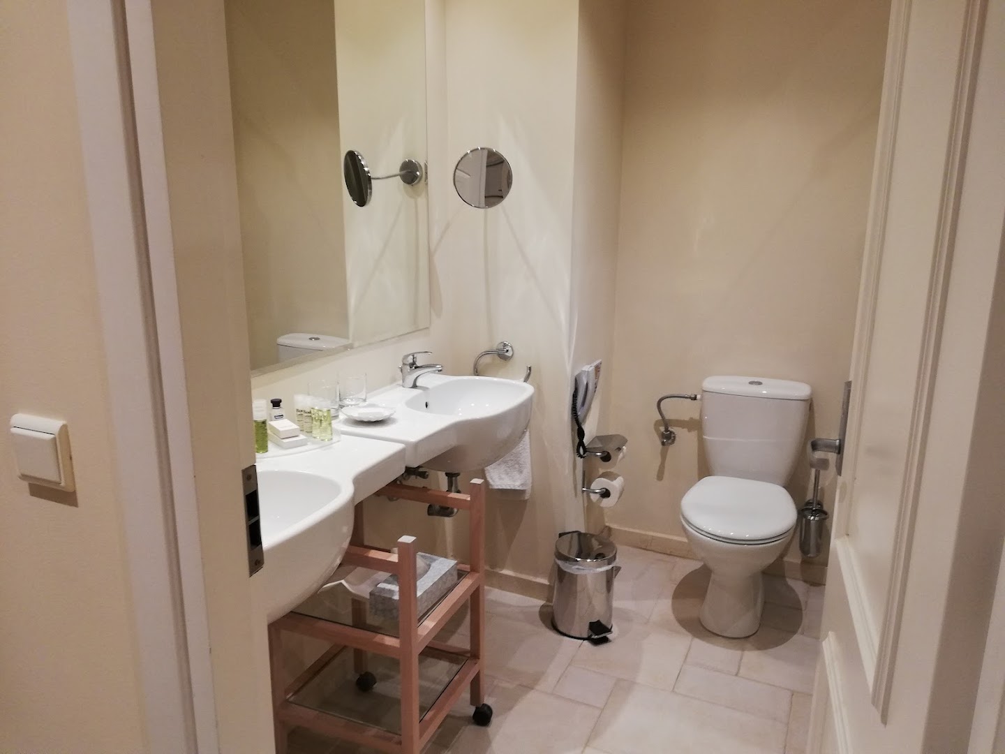 Grecotel Eva Palace viesnīcas numura vannas istaba ar divām izlietnēm, lielu spoguli un gaišu flīžu apdari Korfu kūrortā