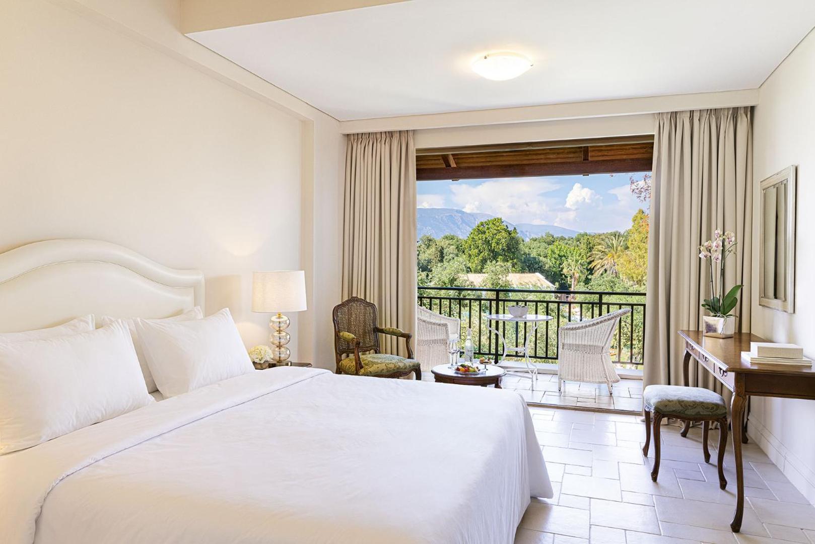 Grecotel Eva Palace numurs ar skatu uz dārzu un kalniem — mēbelēts balkons un elegants darba galds