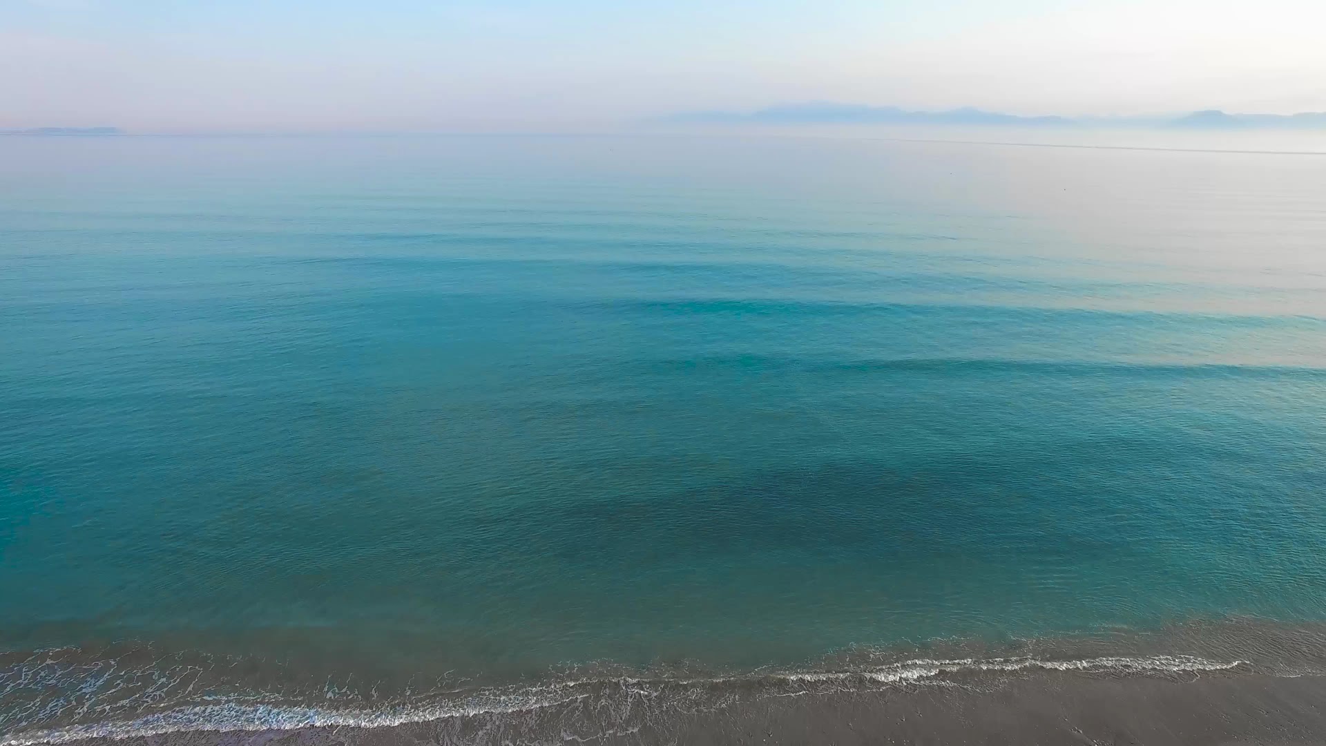 Dzidrs Jonijas jūras ūdens un smilšu pludmale pie Acharavi Beach viesnīcas Korfu salā — mierīgi viļņi un horizonts