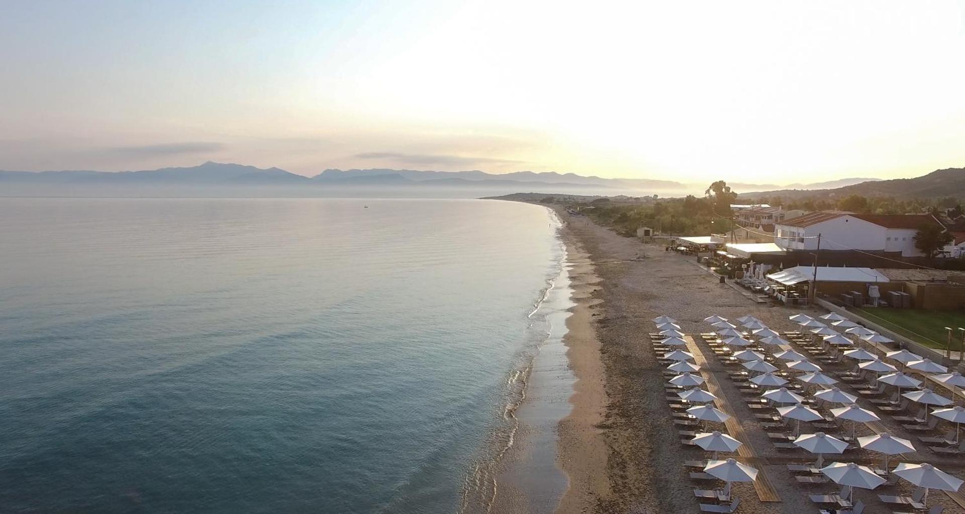 Aerofoto skats uz Acharavi Beach viesnīcas piekrasti un garo smilšu pludmali Korfu salas ziemeļos saullēktā