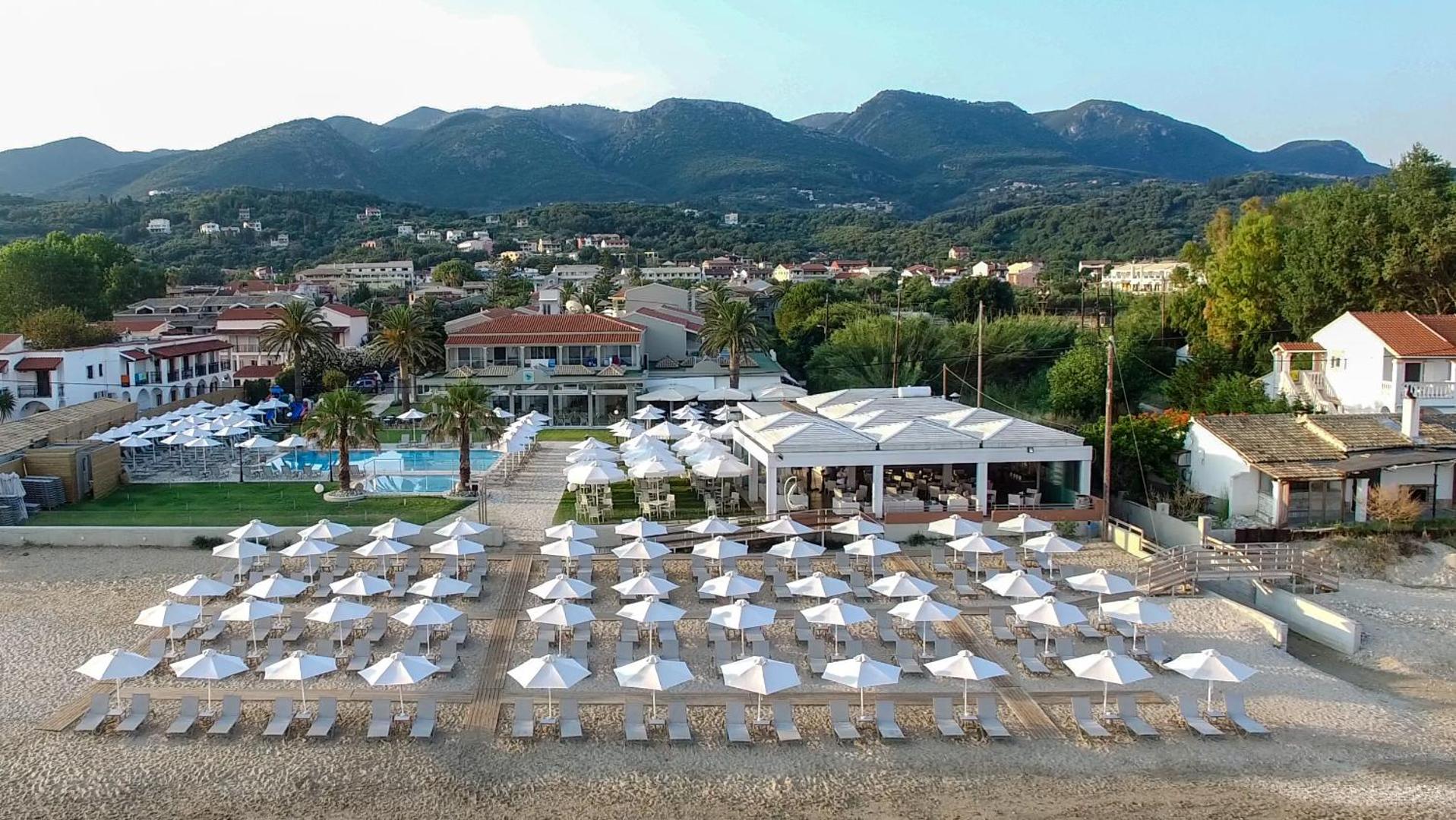 Acharavi Beach viesnīcas panorāmas skats no putna lidojuma uz pludmali, baseinu un kalniem Korfu salas ziemeļos, Grieķijā.