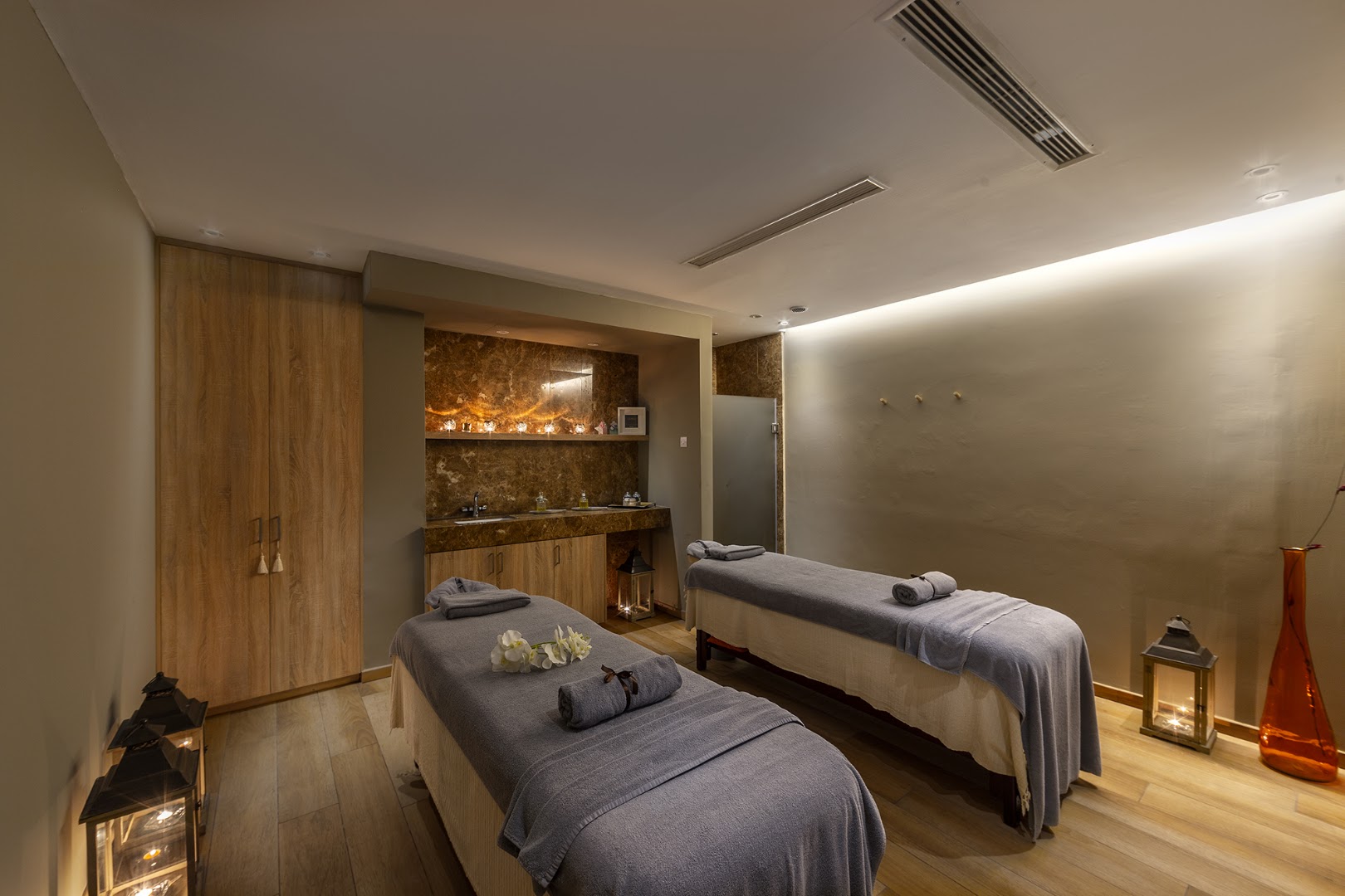 Crystal Springs Beach spa centra masāžas telpa ar divām kušetēm, siltu apgaismojumu un mierpilnu atmosfēru Kiprā