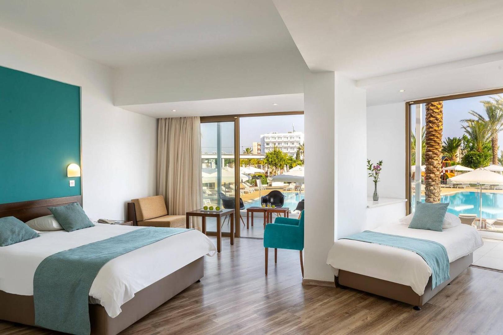 Crystal Springs Beach Hotel gaišs ģimenes numurs ar skatu uz baseinu Protarasā, Kiprā — divguļamā gulta, papildu gulta un balkons.