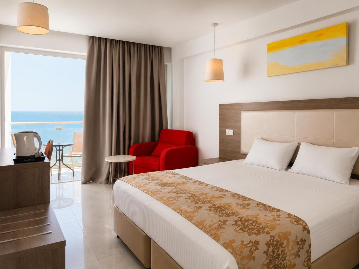 Corfu Hotel numurs ar divguļamo gultu, sarkanu atpūtas krēslu un balkonu, no kura paveras tiešs skats uz jūru