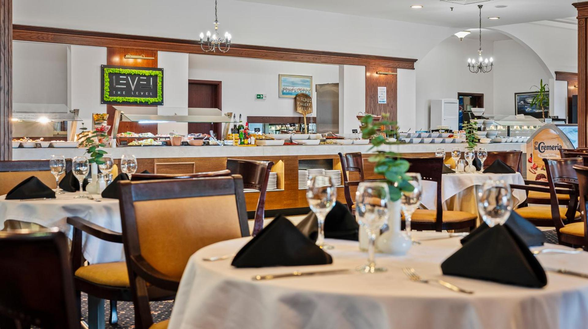 Melia Grand Hermitage The Level restorāna zona ar eleganti klātiem galdiem un izsmalcinātu bufetes līniju