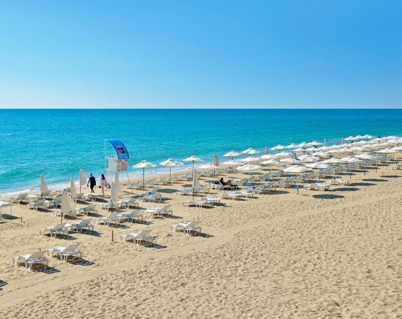 Melia Grand Hermitage privātā pludmale Zelta smiltīs, Bulgārijā — plaša smilšu josla ar baltiem saulessargiem un sauļošanās krēsliem pie zilas jūras