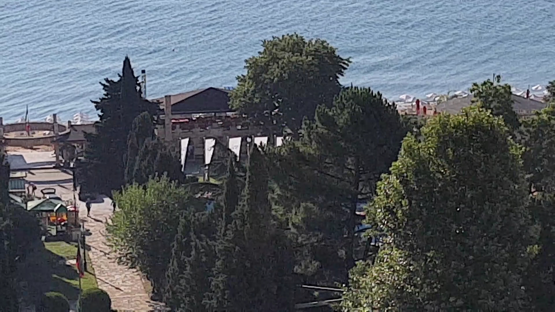 Skats uz Melia Grand Hermitage teritoriju un Melno jūru caur zaļojošiem kokiem — gājēju celiņš un piekrastes panorāma Zelta Smiltīs