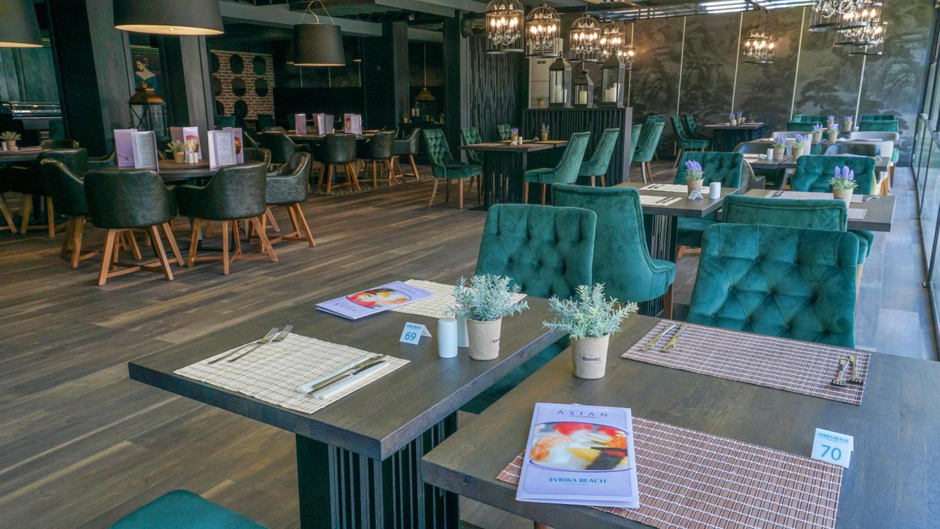 DIT Evrika Beach Club Hotel Āzijas virtuves restorāns ar elegantiem smaragda krāsas krēsliem un stilīgu, tumšu interjeru