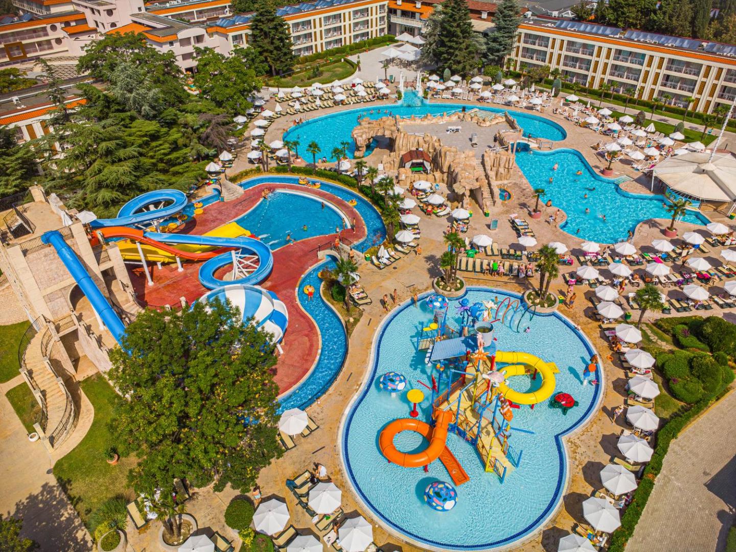 DIT Evrika Beach Club Hotel akvaparks Saulainajā krastā no putna lidojuma — vairāki baseini, krāsaini ūdens slidkalniņi un bērnu ūdens pilsētiņa