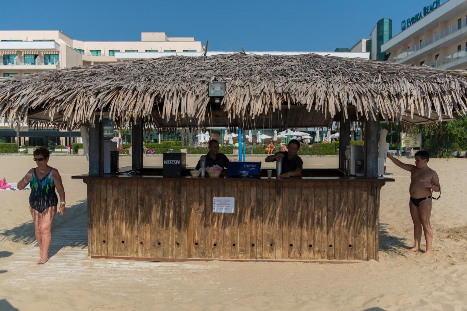DIT Evrika Beach Club Hotel koka pludmales bārs ar niedru jumtu tieši smilšainajā Saulainā krasta piekrastē