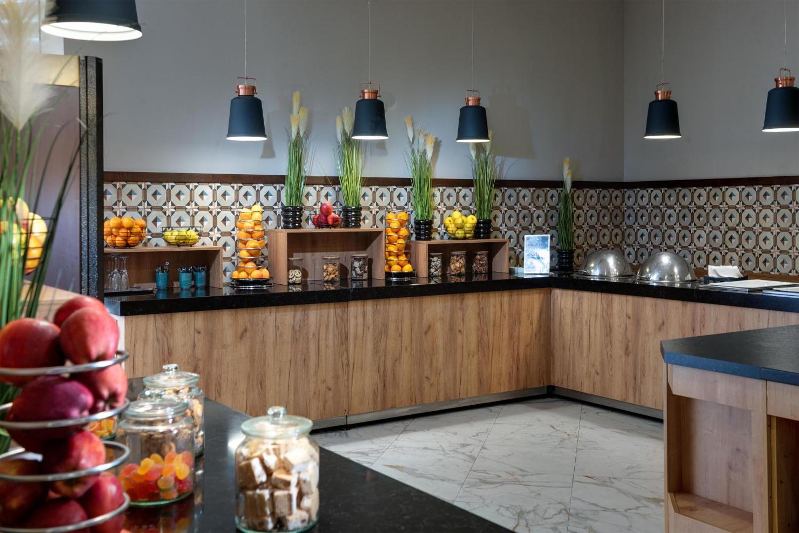 Best Western Plus Premium Inn bufetes zona ar svaigiem augļiem, uzkodām un dekoratīviem elementiem uz koka virsmām