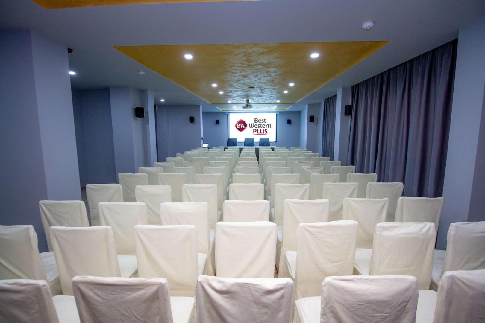Plaša Best Western Plus Premium Inn konferenču zāle ar baltiem krēsliem un multimediju aprīkojumu pasākumiem Saulainajā Krastā