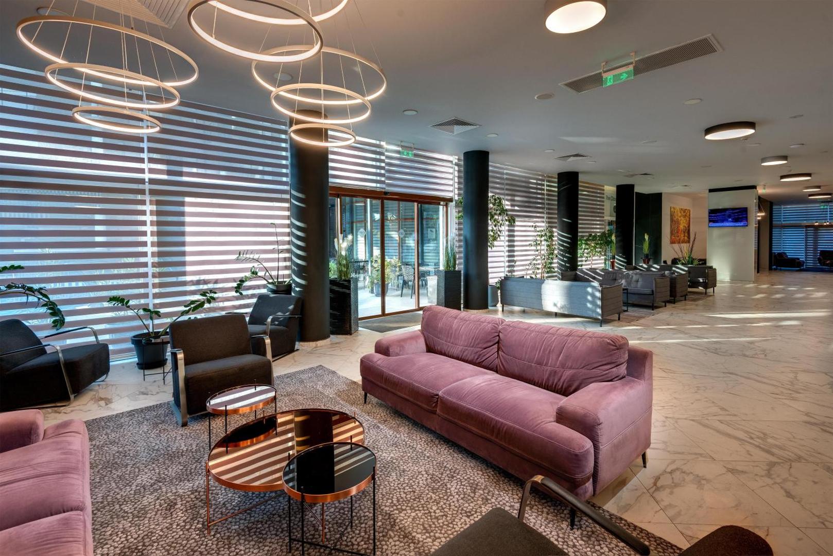 Best Western Plus Premium Inn modernā atpūtas zona ar stilīgiem dīvāniem, dizaina gaismekļiem un plašiem logiem Saulainā krasta kūrortā