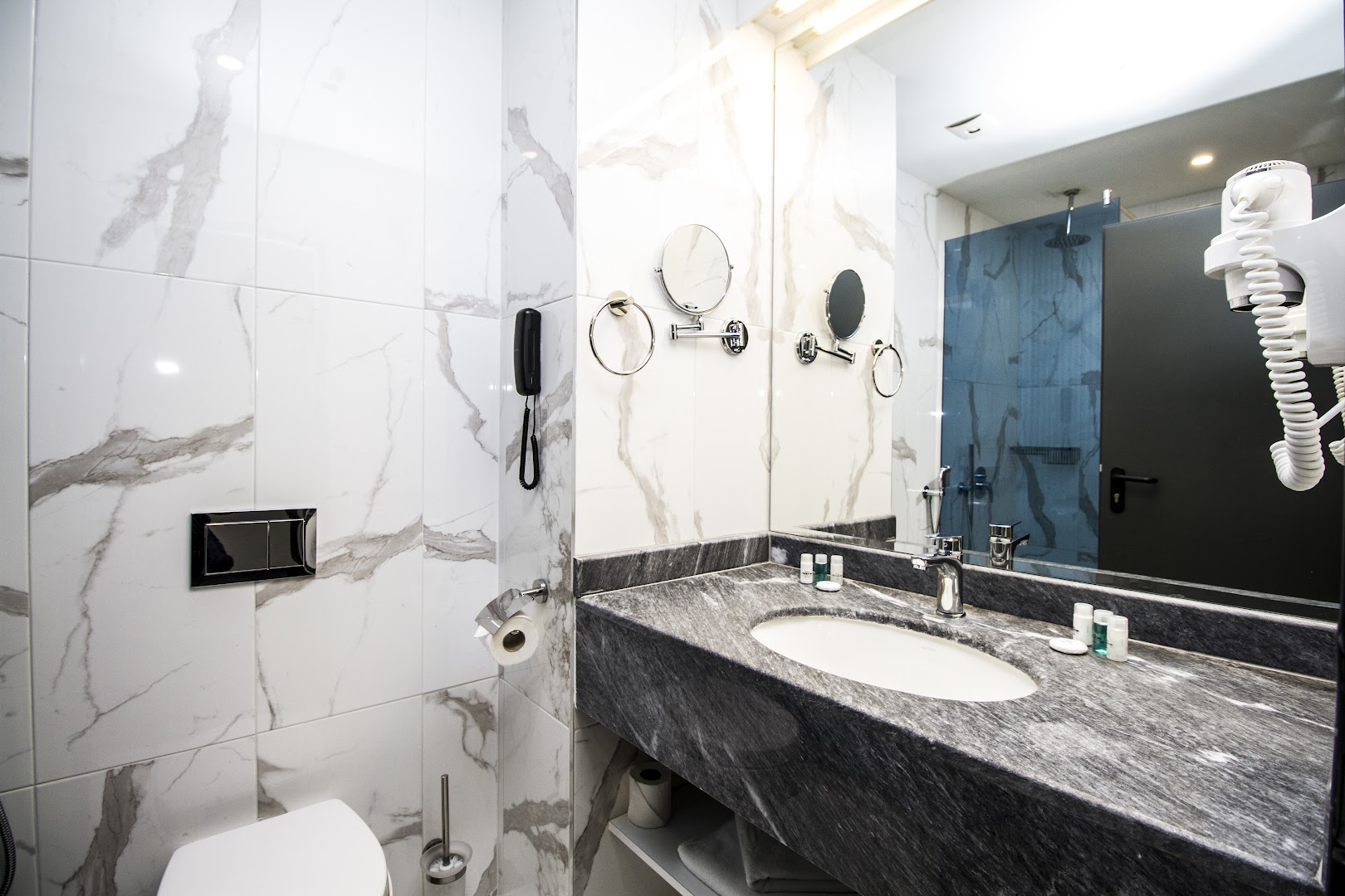 Mūsdienīgs Best Western Plus Premium Inn numura vannas istabas interjers ar marmora apdari, plašu spoguli un dušas zonu