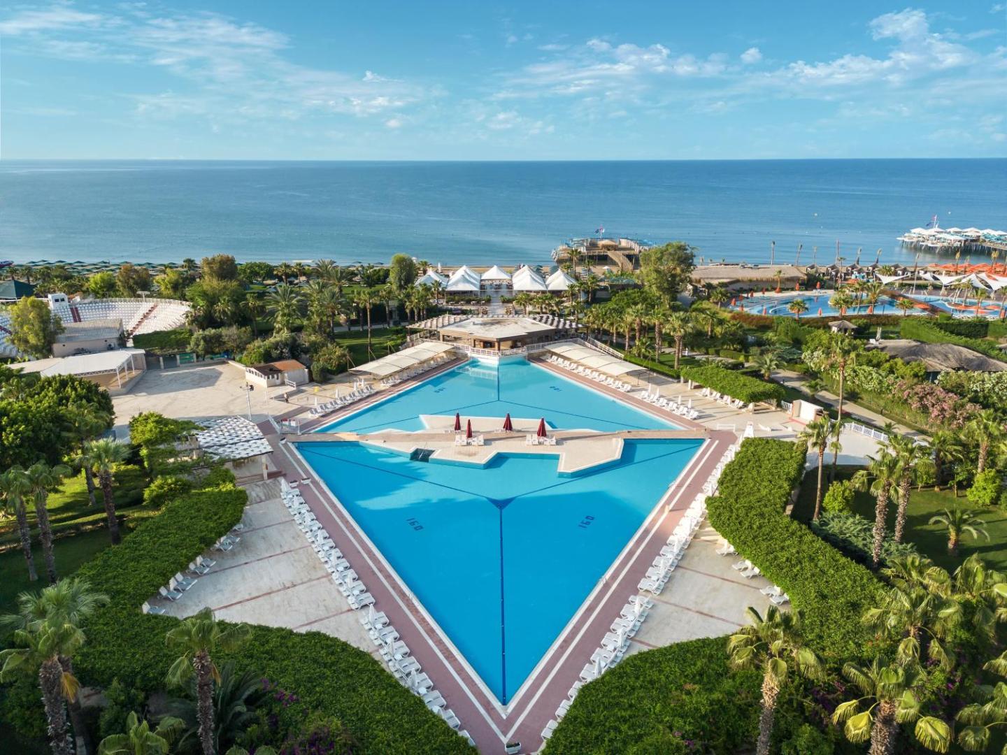 Kaya Belek kūrorta panorāmas skats uz lielo āra baseinu, zaļo teritoriju un Vidusjūras piekrasti Antaljas reģionā, Turcijā