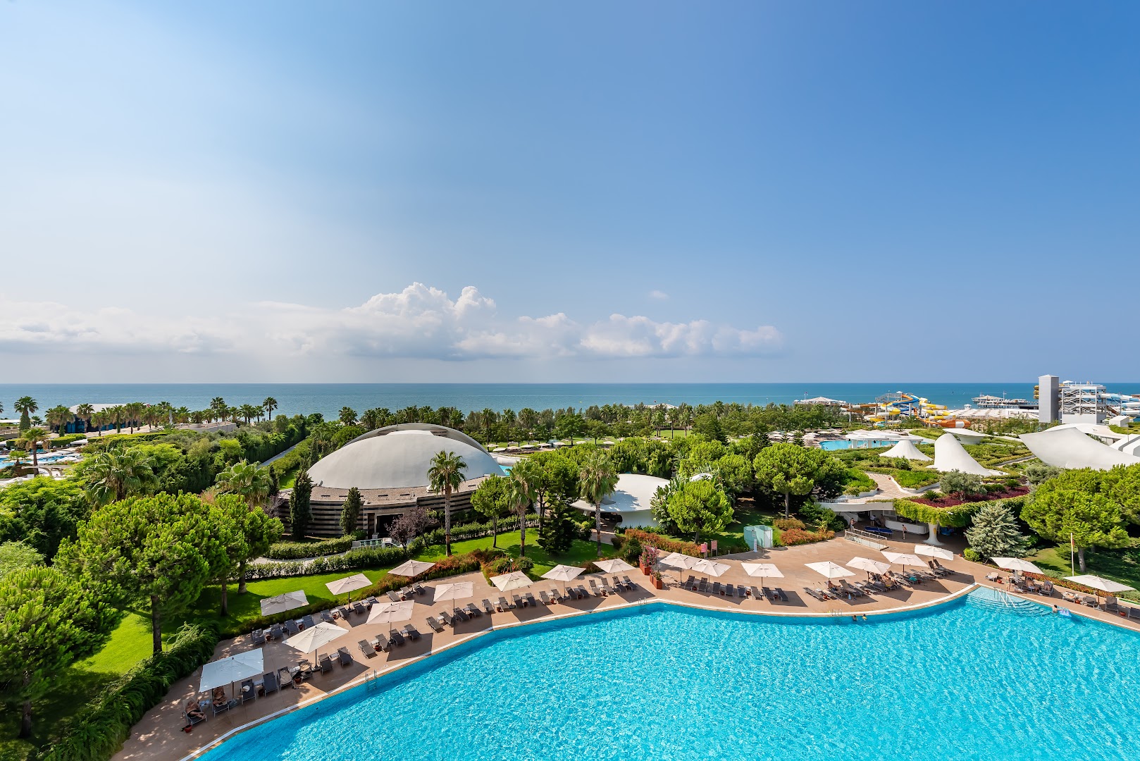 Cornelia Diamond Golf Resort & Spa teritorijas skats no augšas — baseini, zaļojoši dārzi un akvaparks piekrastes zonā Belekā