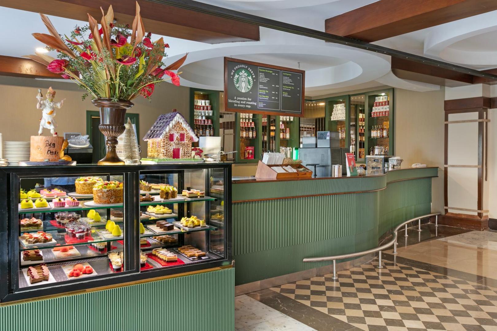 Dobedan Exclusive Hotel & Spa kafejnīca ar Starbucks kafiju un plašu kūku izvēli vitrīnā — mājīgs interjers ar zaļiem akcentiem