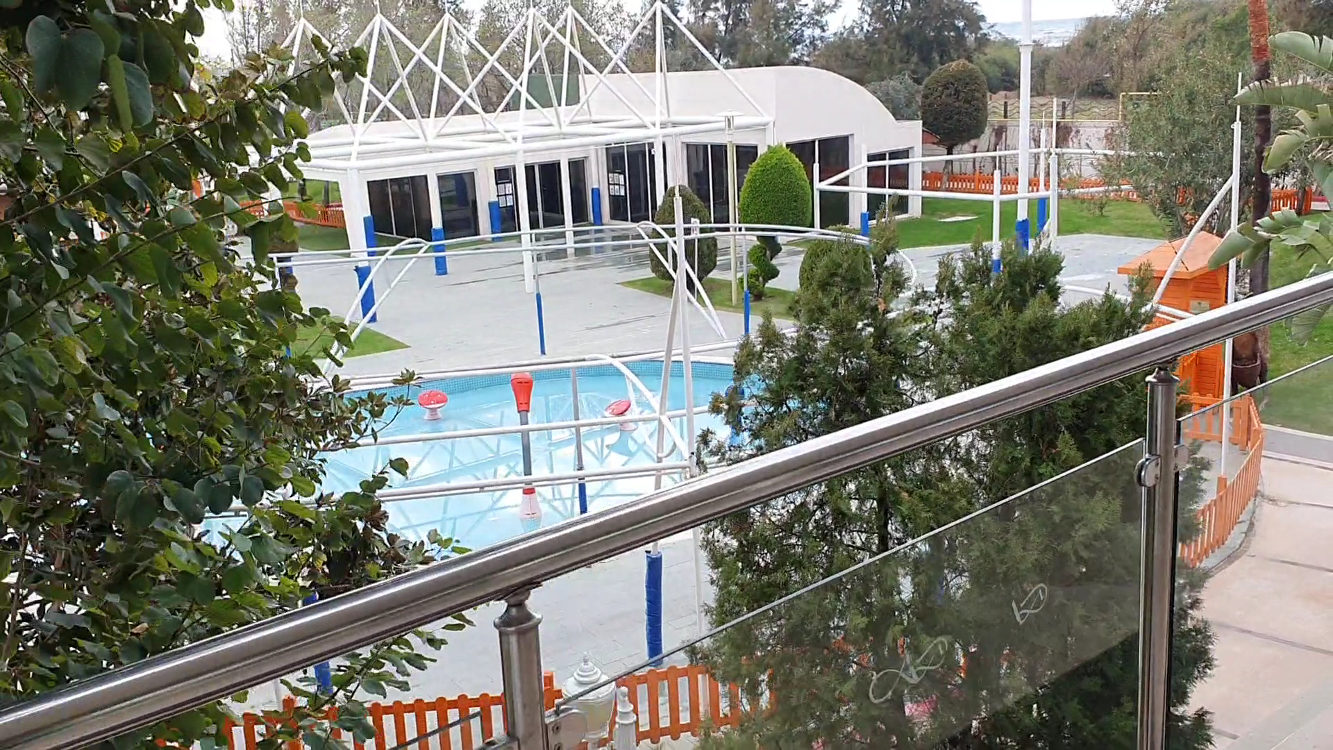 Skats no Dobedan Exclusive Hotel & Spa balkona uz bērnu atpūtas zonu un baseinu, ko ieskauj zaļi koki