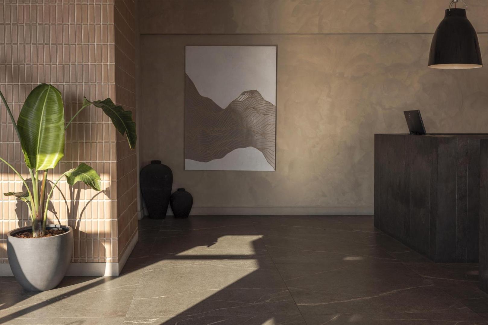 Domes Aulus Elounda Resort lobby interjers ar dizaina elementiem, lielu augu podā un siltu apgaismojumu Krētas viesnīcā