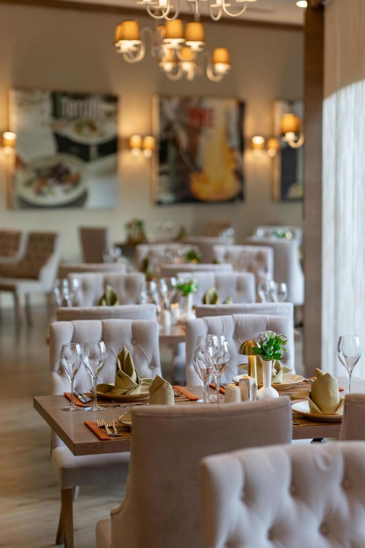 Limak Atlantis De Luxe a la carte restorāna interjers ar eleganti klātiem galdiem, mīkstiem krēsliem un siltu apgaismojumu