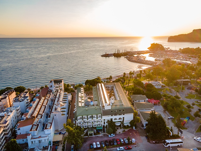 Aerofoto skats uz L'ancora Beach Hotel saulrietā — viesnīcas komplekss pie Kemeras ostas un Vidusjūras piekrastes