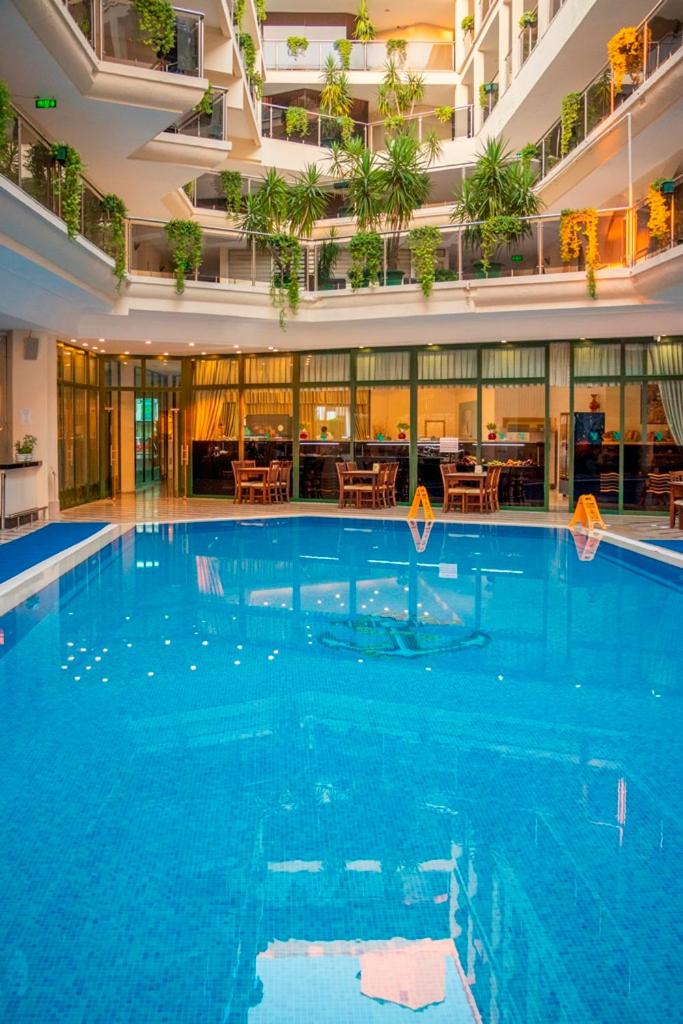 L'ancora Beach Hotel iekšpagalms ar segtu baseinu un atpūtas zonu — apkārt izvietoti balkoni ar zaļojošiem augiem un restorāna galdiņi