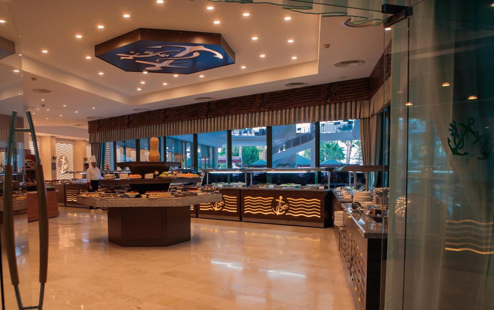 L'ancora Beach Hotel bufetes zona ar plašu ēdienu izvēli, augļiem un dekoratīvu enkura simbolu pie griestiem