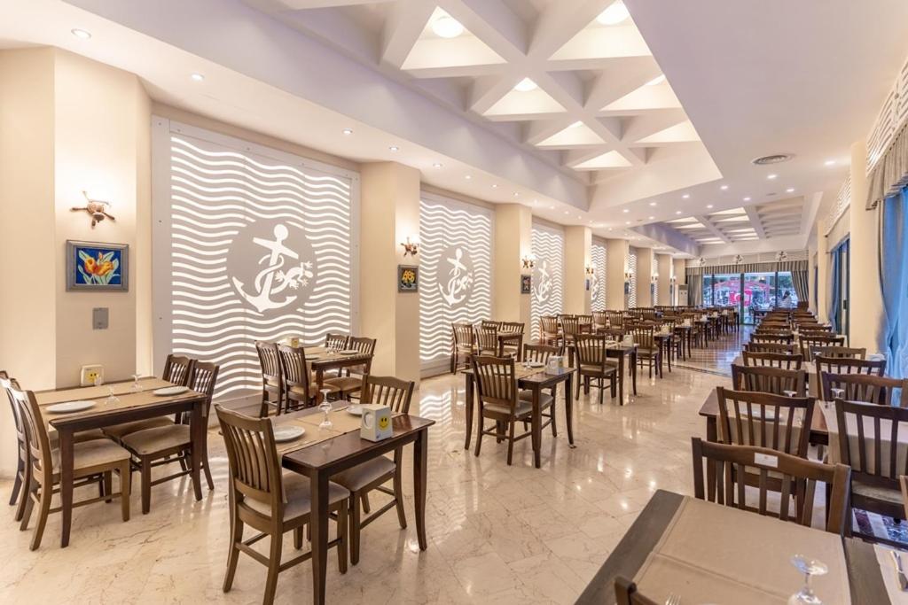 L'ancora Beach Hotel galvenais restorāns ar koka galdiem, modernu apgaismojumu un dekoratīviem sienas paneļiem