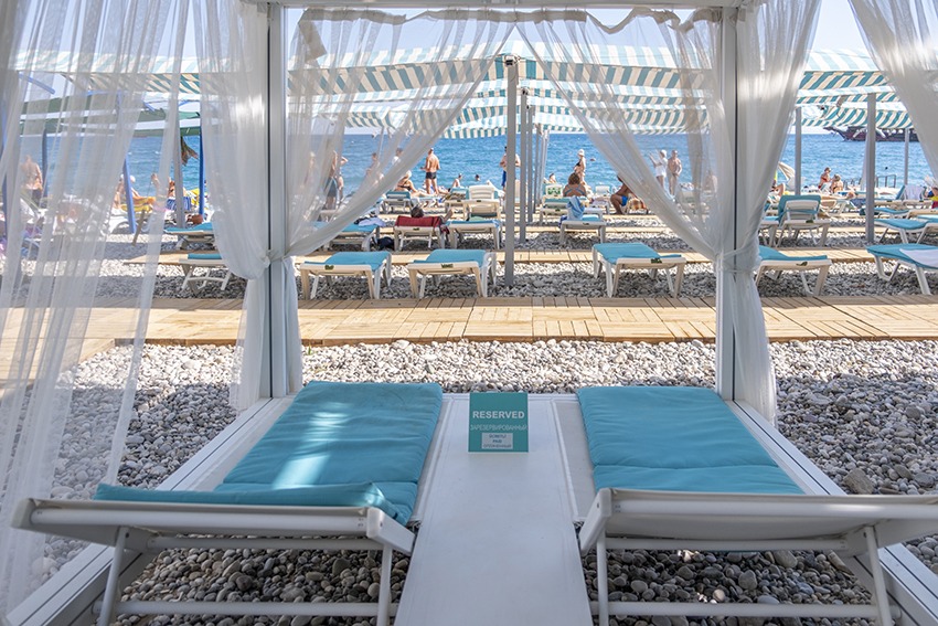 L'ancora Beach Hotel pludmales atpūtas nojume ar baltiem aizkariem un skatu uz Vidusjūru un saulessargiem