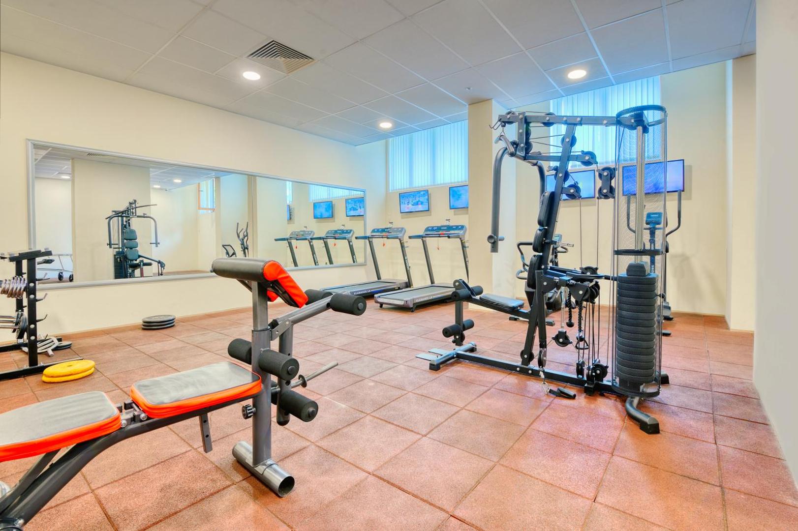 Viesnīcas Golden Line fitness centrs ar skrejceļiem, spēka trenažieriem un lielu spoguli aktīvai atpūtai ceļojuma laikā