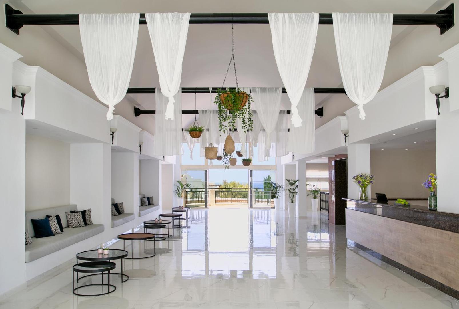 Louis Paphos Breeze viesnīcas lobby un recepcijas zona — plaša, gaiša telpa ar modernu dizainu un atpūtas stūrīšiem