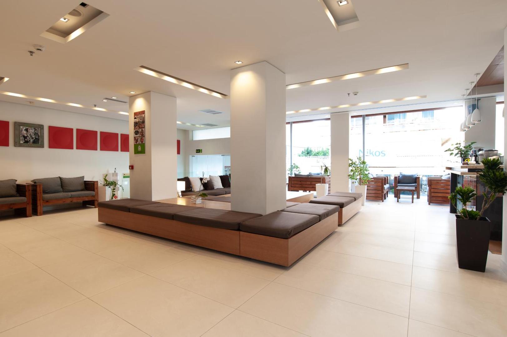 Plašs Atlantis Boutique City Hotel vestibils ar gaišām flīzēm, ērtiem sēdekļiem un modernu apgaismojumu Rodas pilsētas viesnīcā.