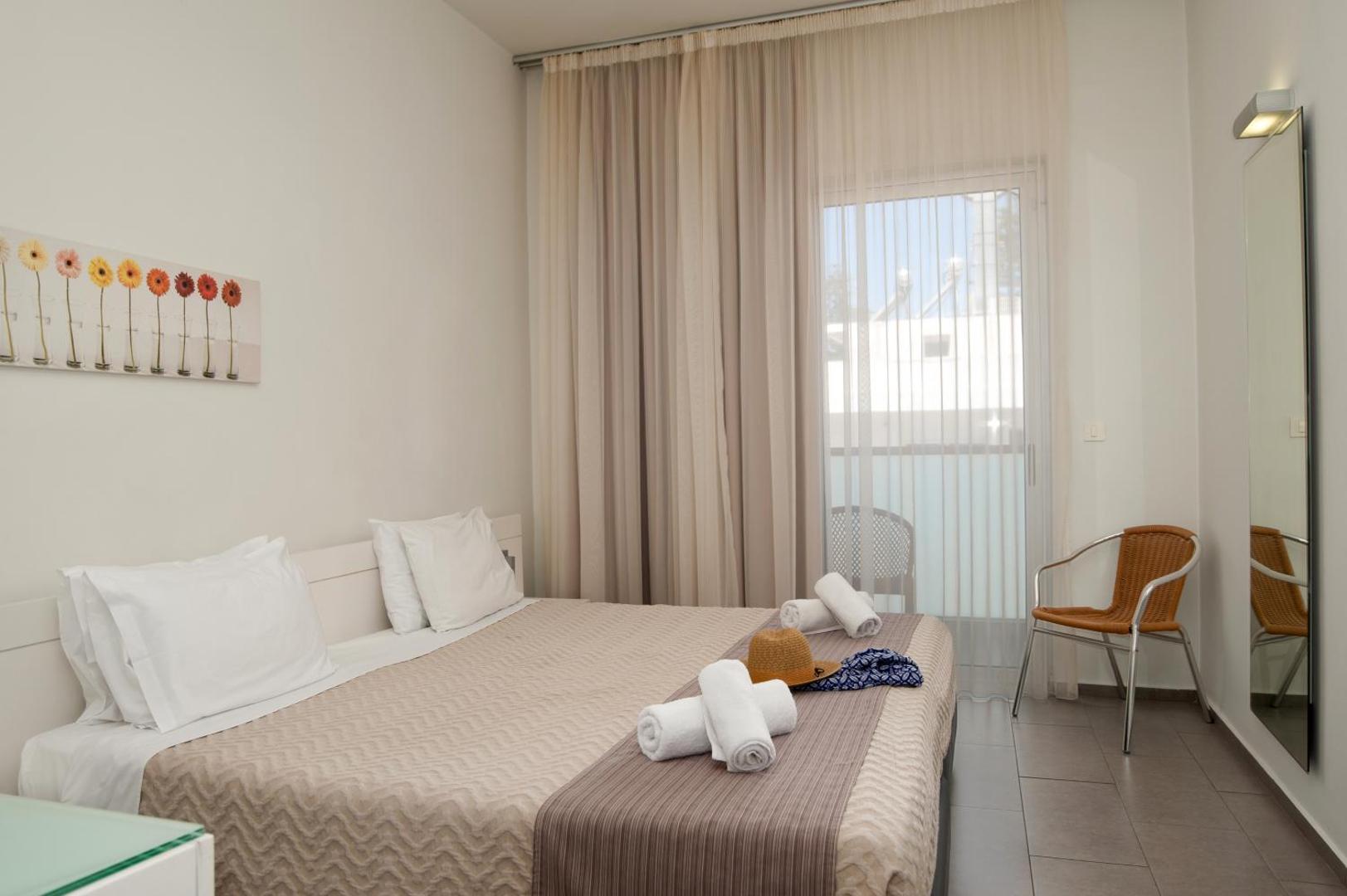 Atlantis Boutique City Hotel gaišs divvietīgs numurs Rodas pilsētā ar balkonu, lielu spoguli un dekoratīviem ziedu motīviem pie sienas