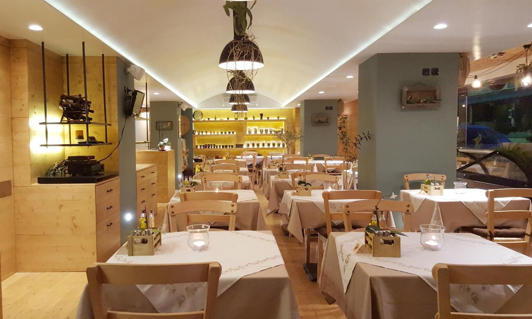 Atlantis Boutique City Hotel restorāna zāle ar koka mēbelēm, siltu apgaismojumu un eleganti klātiem galdiem vakariņām