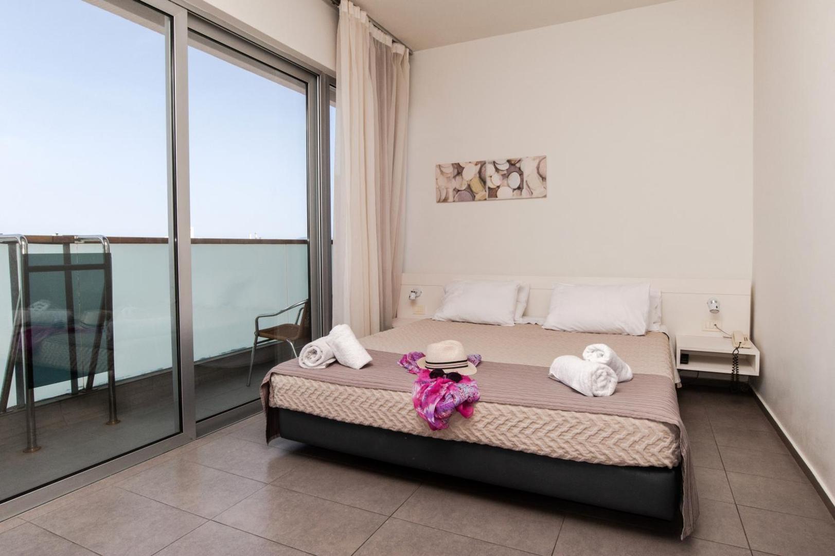 Atlantis Boutique City Hotel numurs ar plašām stikla bīdāmajām durvīm uz privātu balkonu un modernu interjeru Rodā