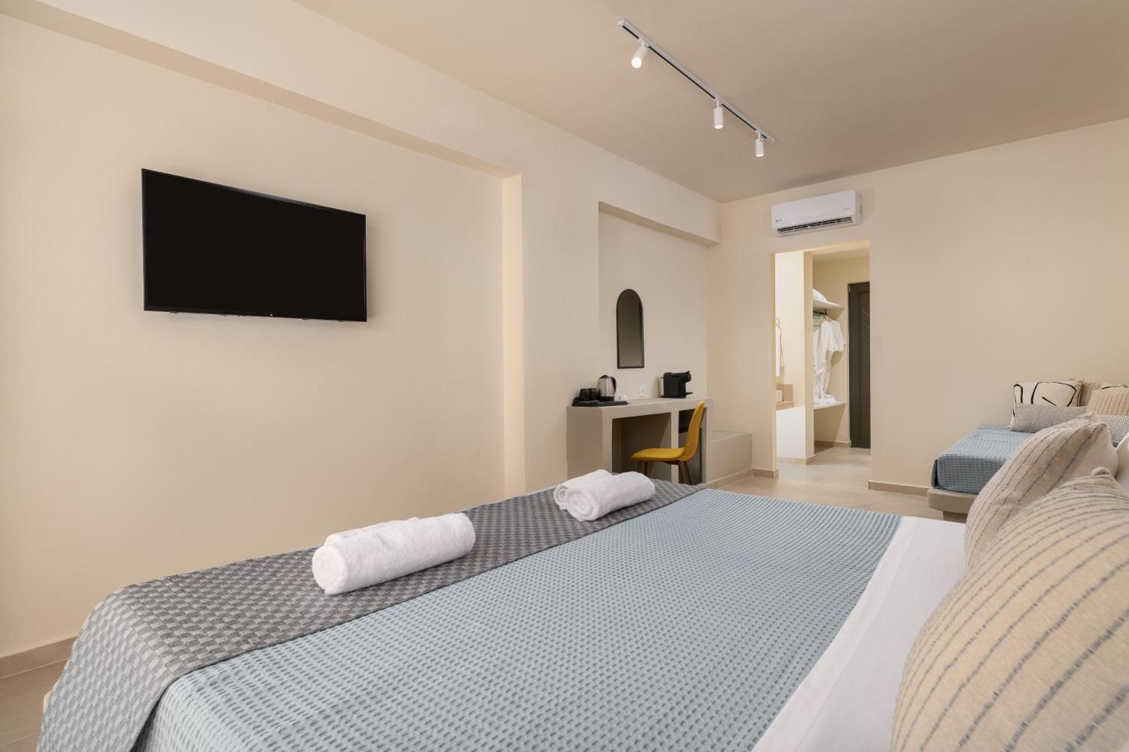 Moderns Olive Garden Hotel numura interjers ar divguļamo gultu, gaišām sienām, televizoru un ieeju vannasistabā