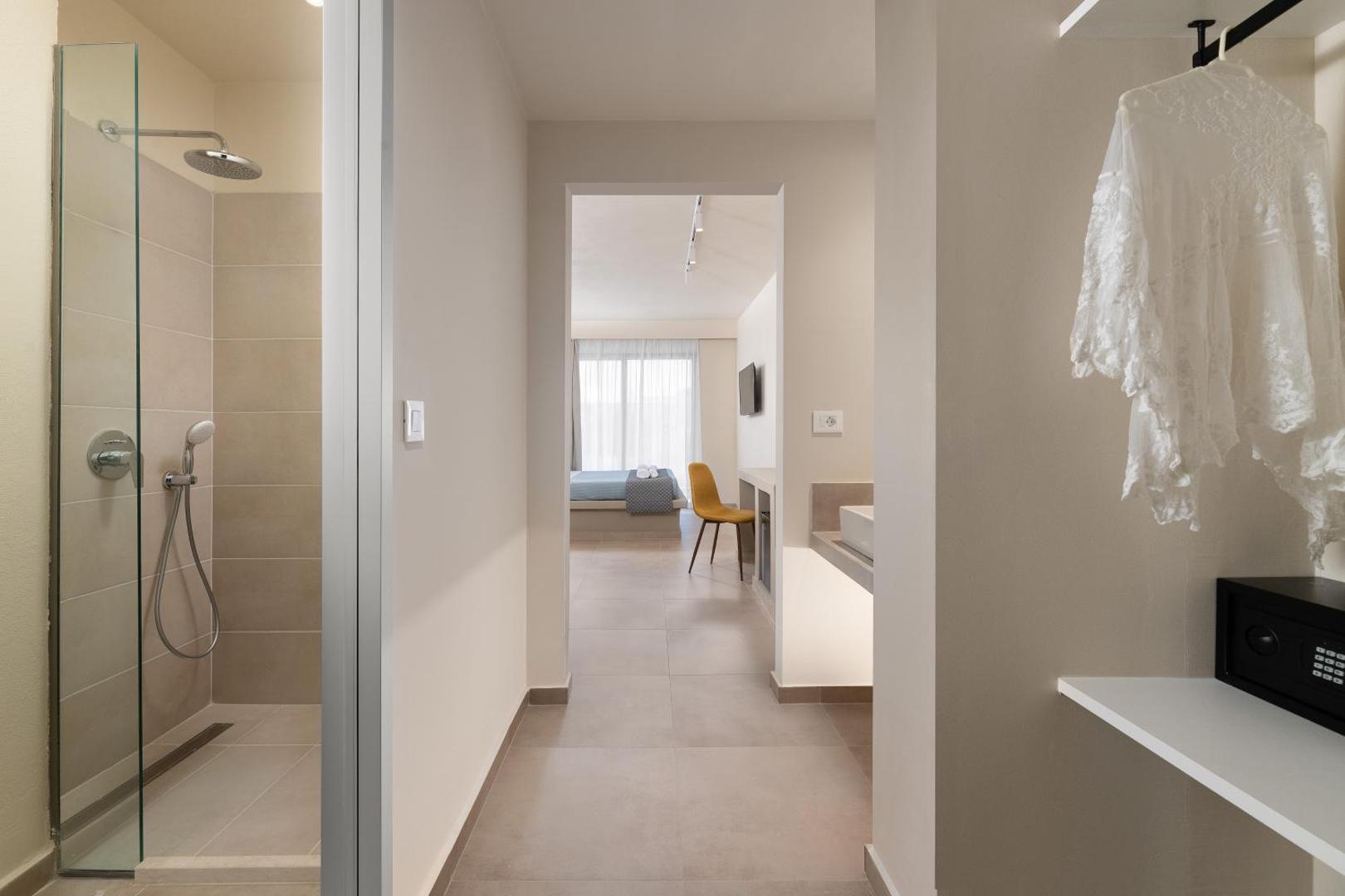 Olive Garden Hotel moderns numurs ar dušas zonu, gaišu interjeru un skatu uz guļamistabu — mūsdienīgs dizains