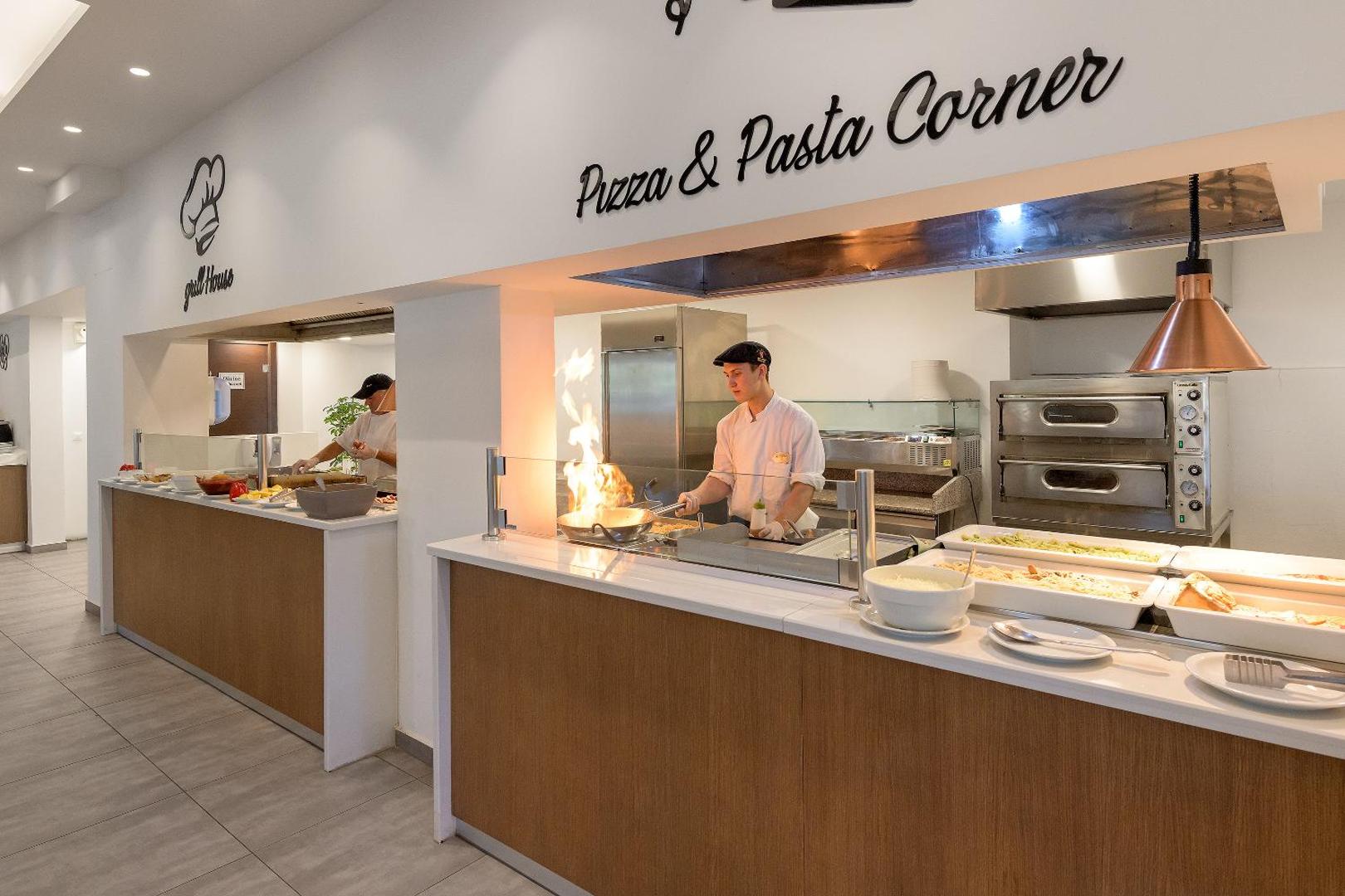 Olive Garden Hotel atvērtā tipa virtuve, kur pavārs gatavo picu un pastu uz dzīvas uguns viesu acu priekšā
