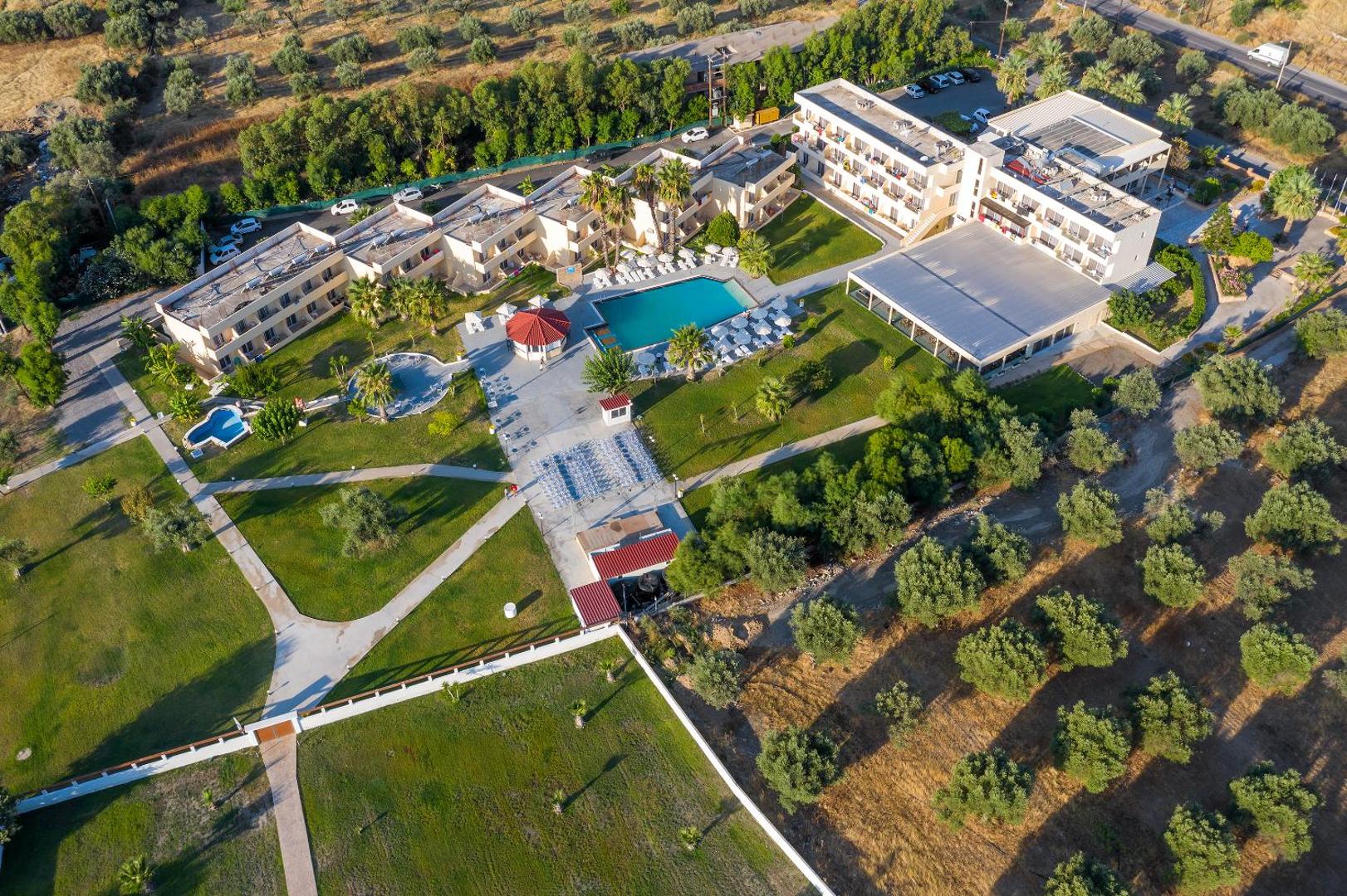 Olive Garden Hotel Rodā skats no putna lidojuma — viesnīcas korpusi, baseins un plaša dārza teritorija olīvkoku ieskāvumā