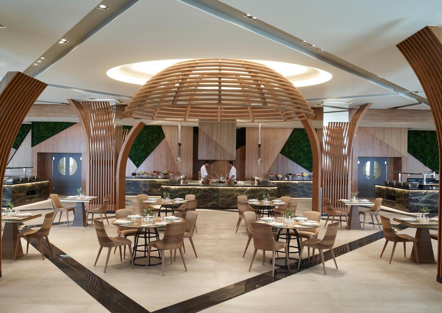 Mayia Exclusive Resort & SPA galvenais restorāns ar modernu koka kupola dizainu, bufetes zonu un elegantiem galdiņiem Rodas salā.