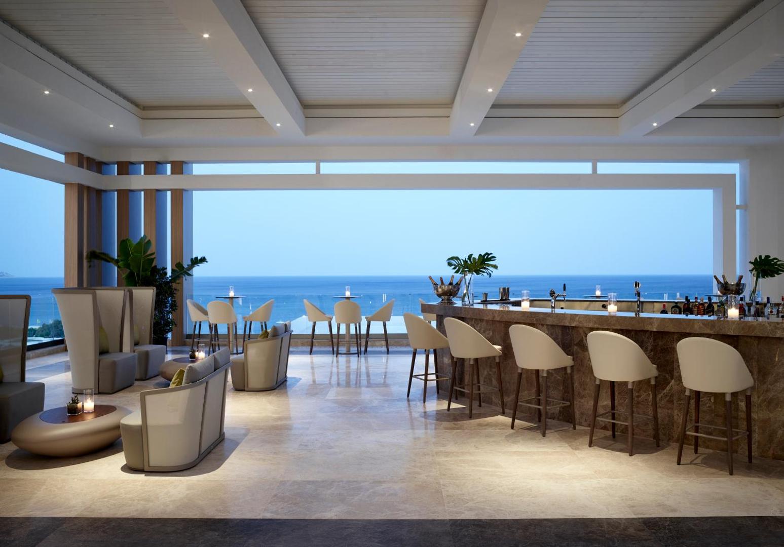 Mayia Exclusive Resort & SPA āra terases bārs ar skatu uz jūru saulrietā, modernām mēbelēm un marmora leti Rodas salā