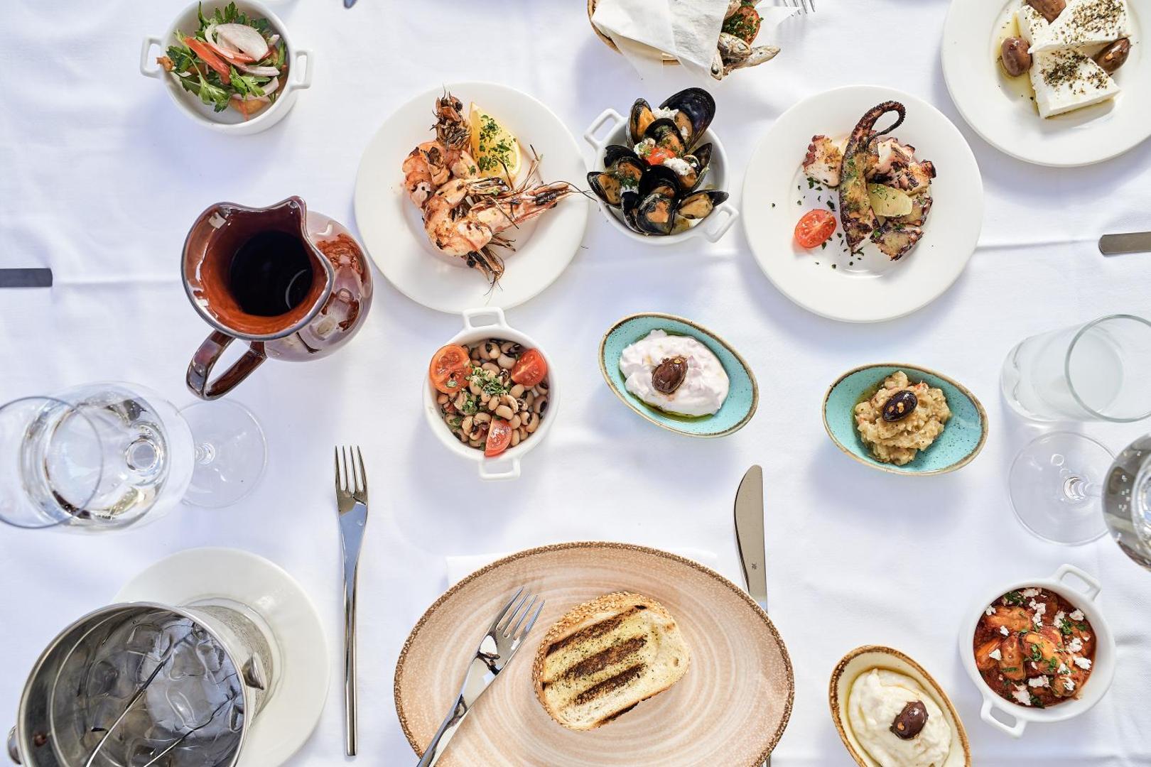 Grieķu virtuves uzkodu galds Mayia Exclusive Resort & SPA — mīdijas, garneles, astoņkājis un tradicionālās mērces baltā noformējumā