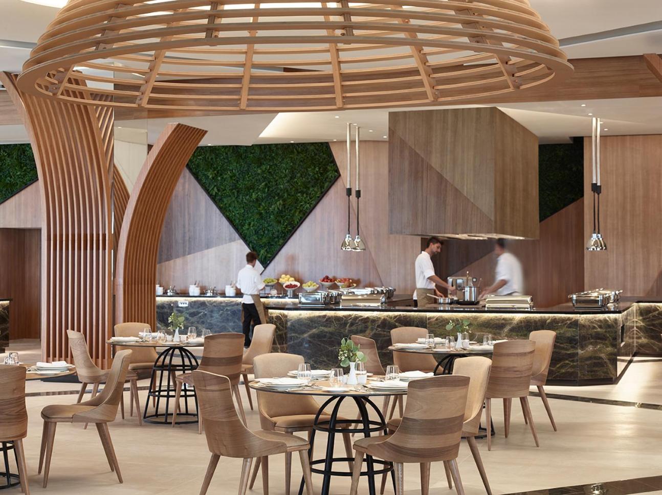 Tuvplāns Mayia Exclusive Resort & SPA restorāna gatavošanas stacijai ar pavāriem un dekoratīviem koka elementiem interjerā.