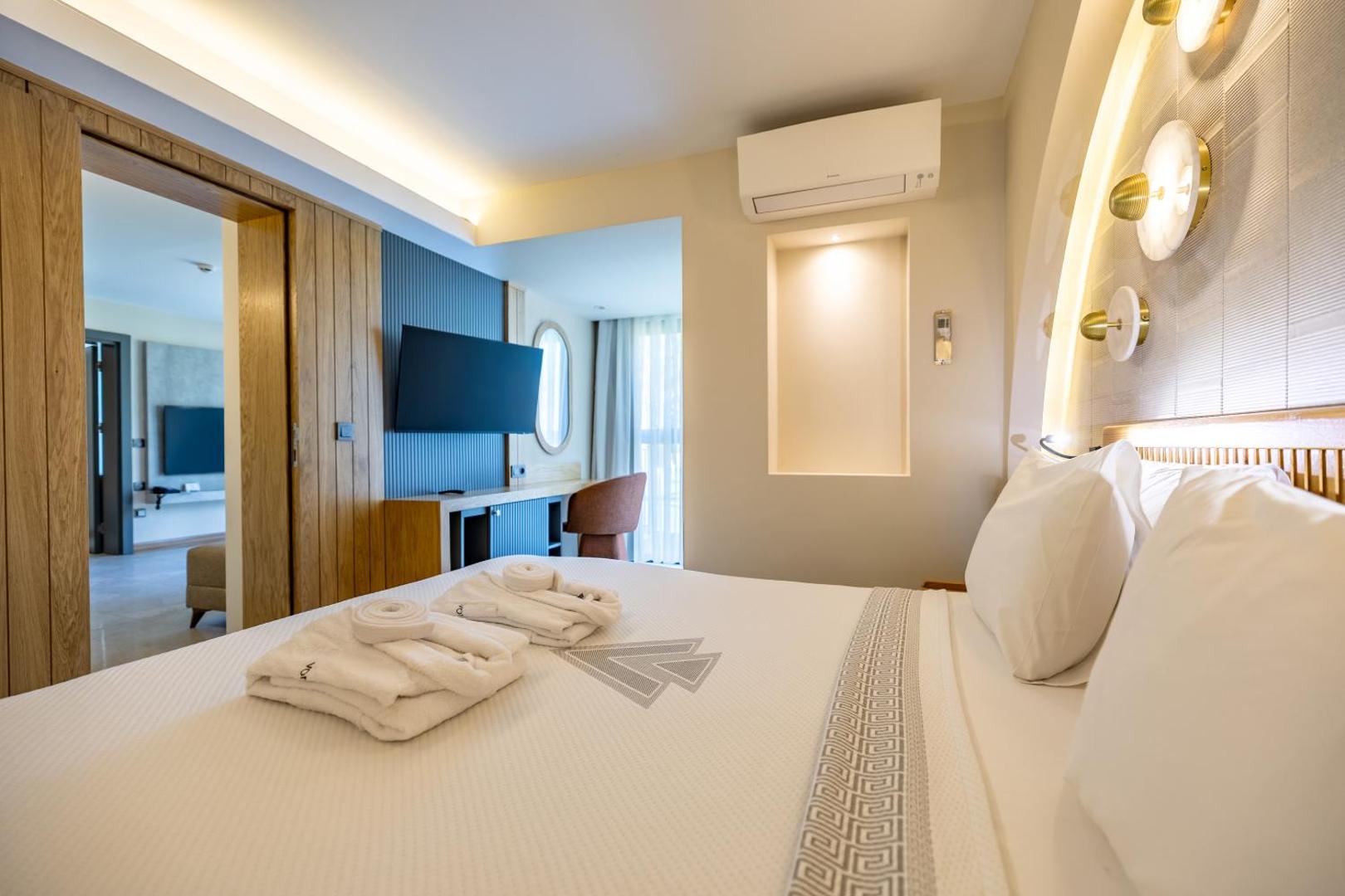 VONRESORT Golden Beach moderns viesnīcas numurs ar gaišu interjeru, divguļamo gultu, peldmēteļiem un sienas televizoru Turcijā