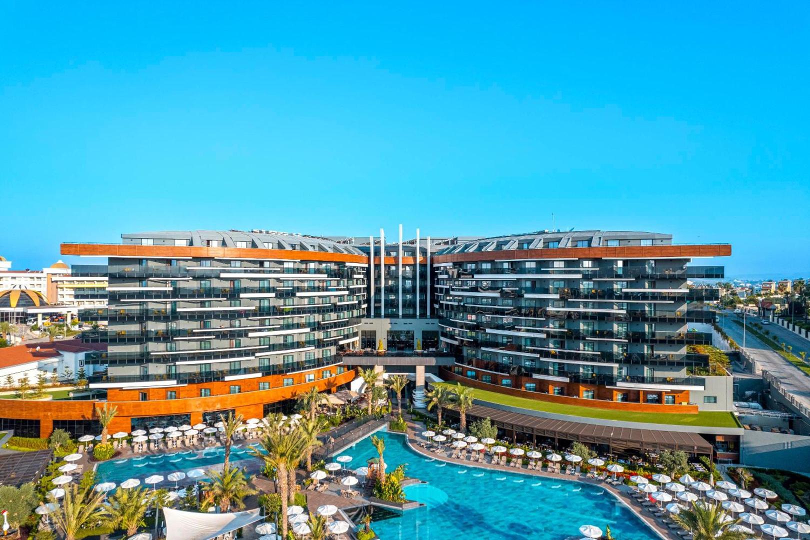 Kirman Calyptus Resort & SPA modernā arhitektūra un plašais āra baseins ar atpūtas zonu Sides reģionā, Turcijā dienas gaismā